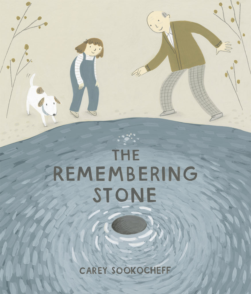 The Remembering Stone by Carey Sookocheff. A girl and an older man with light skin tone, and a white and brown dog, stand on the edge of a body of water, facing us. A stone the man has just thrown skips toward us. The girl has shoulder-length brown hair with a hair bow, and wears blue overalls, a long-sleeved white and grey striped shirt, and tan shoes. The man is bald with grey hair on the side of his head, and wears a brown cardigan over a white collared shirt, grey checked pants, and grey shoes. 