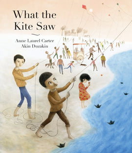  Cover: “What the Kite Saw. Anne Laurel Carter. Akin Duzakin.” The image is of a long, sandy beach where people fly kites, a man pulls a food cart, and a small girl with light skin tone stares at her ice cream cone. In the foreground, two boys hold kite strings. They have light skin tone, short dark hair, long sleeved shirts and pants with the legs rolled up. They are barefoot. Two buildings and four trees are visible in the background. Black origami sailboats float on the water. 