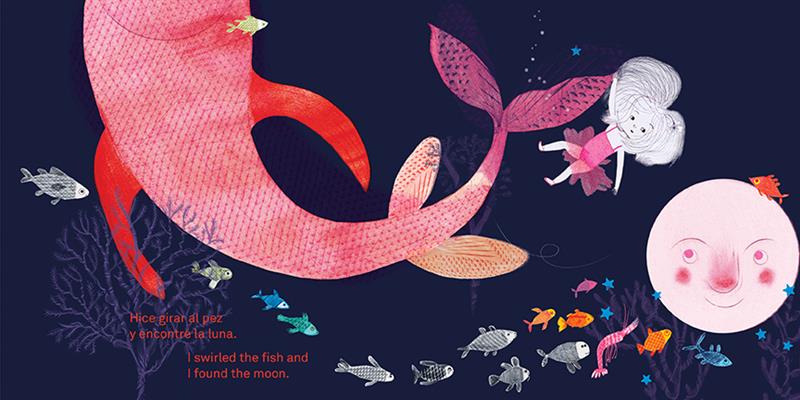  Underwater, the water is black. A girl in a pink tutu hangs on to the tail of a giant pink fish. Smaller fish in blue, orange, and black and white swim around. The moon is underwater and is pink. It has a face and watches the girl. Small blue stars surround it. A bare tree and coral come up from the ground. Text: I swirled the fish and I found the moon. Text is also in Spanish. 
