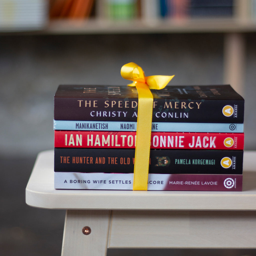  A photo of copies of The Speed of Mercy, Manikanetish, Bonnie Jack, The Hunter and the Old Woman,  and A Boring Wife Settles the Score sitting on a bench, tied together with a bright yellow ribbon.  