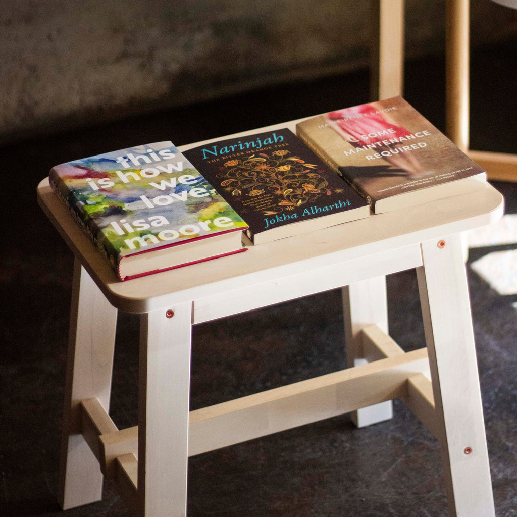  A photo of copies of This Is How We Love, Narinjah, and Some Maintenance Required in the Anansi book shop. They are stacked on a wooden shelf. 