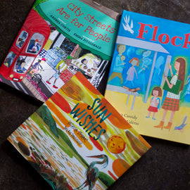  A photo of copies of City Streets Are For People, Flock, and Sun Wishes, all hardcover picture books, laying on a carpet. 